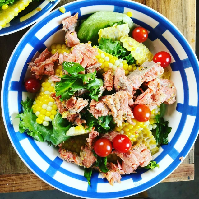 a close up of a bowl of food with corn and tomatoes