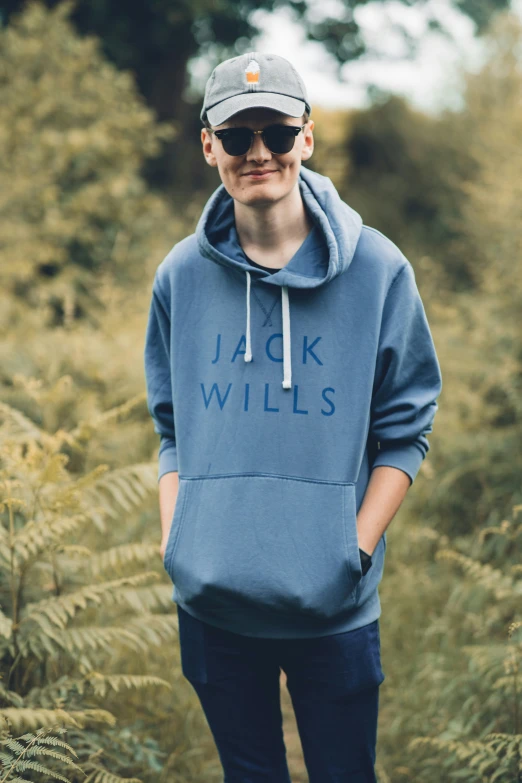 a man standing in a field wearing a blue sweatshirt with the words jack willis on it