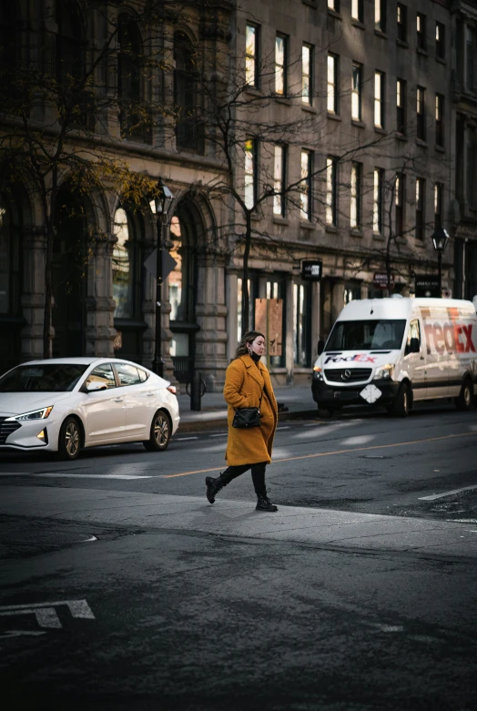 woman crossing street in urban area near taxi cabs and building