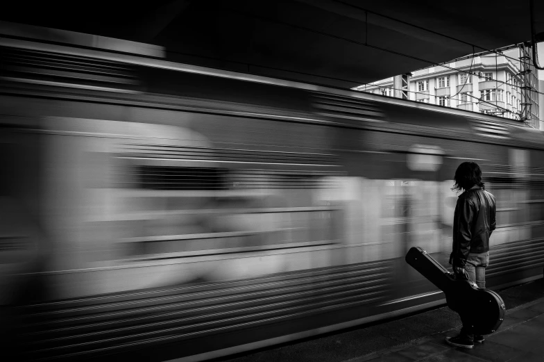 black and white pograph of person walking beside a train