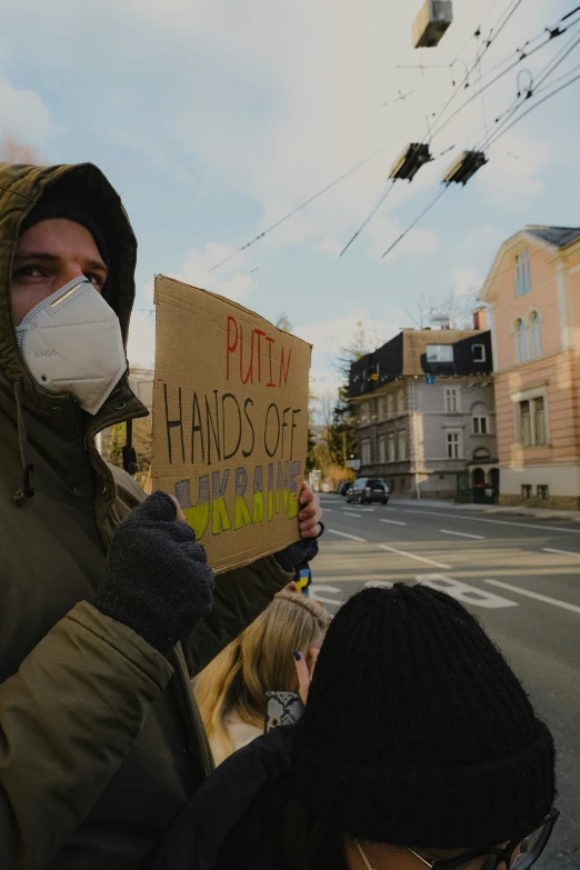 people wearing masks on holding protest signs with masks on