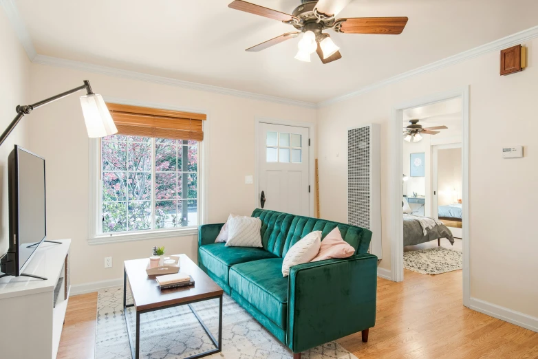 a living room has a green sofa and a ceiling fan