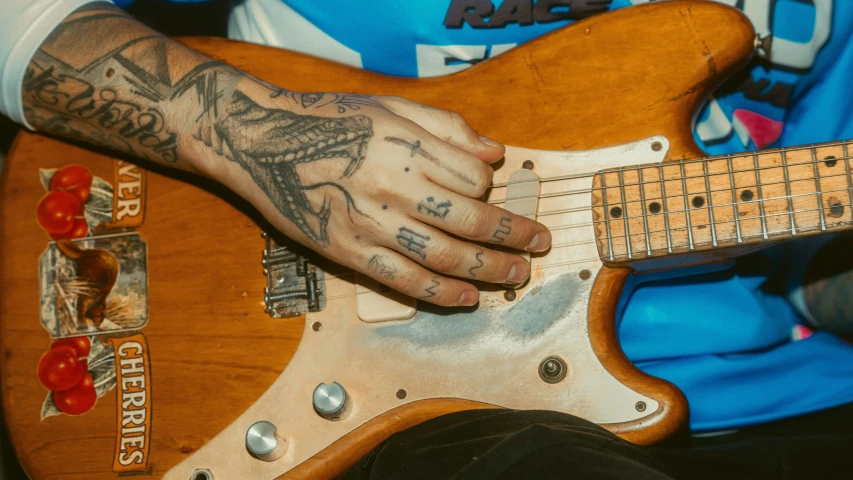 an older man with tattooed arm holding a guitar