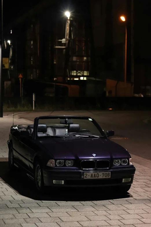 the black car is parked on the cobblestone ground