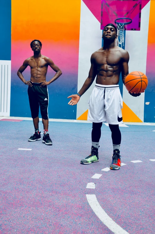 a couple of young men standing on top of a basketball court