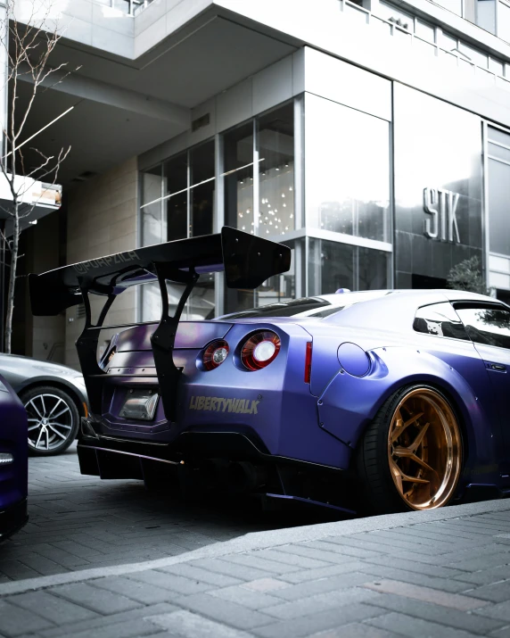 a purple car with gold rims on it parked in front of a building