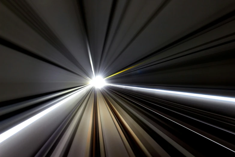 a speeding train going towards the end with the light at the end
