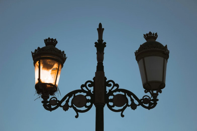 an old fashioned street light lit by the dusk