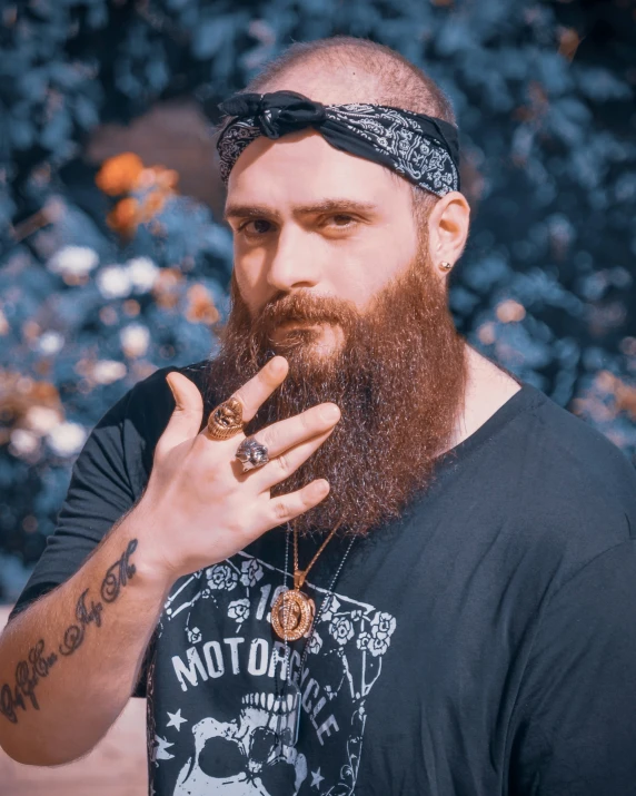 a man with a long red beard and bandana on, smoking a cigarette