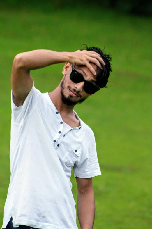 a man in a white shirt holding his arm on top of his head