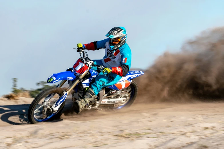 a person on a motorcycle riding in the sand