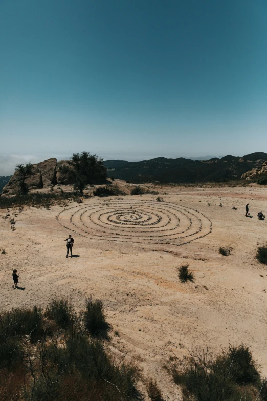 a man stands in the middle of a desert with an enormous, circular rock circle on top of it