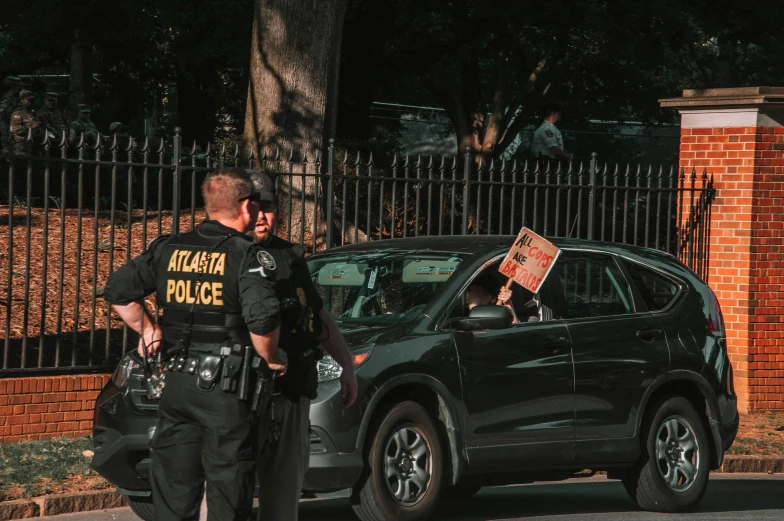 two policemen and a police car are parked in front of a fenced off area