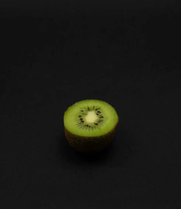 a half cut kiwi fruit is sitting on a black surface