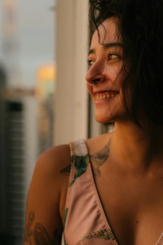 a woman in floral top with tattoos smiles