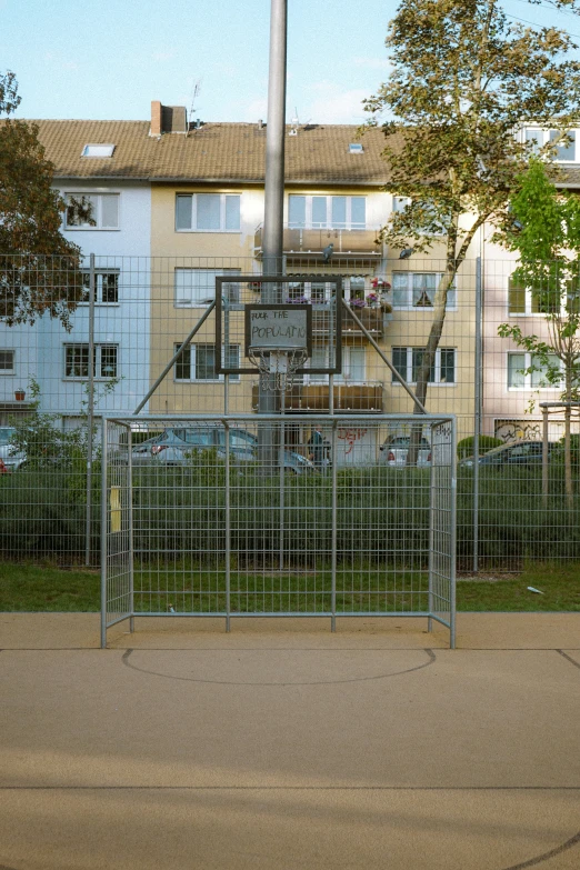 a fence surrounds a basketball court with a tall building behind it