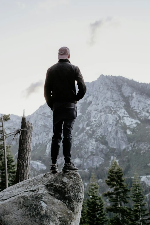 a man standing on top of a big rock in the mountains