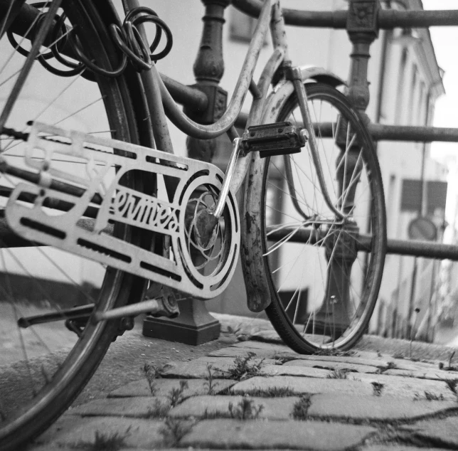 black and white image of an old bicycle parked next to a railing