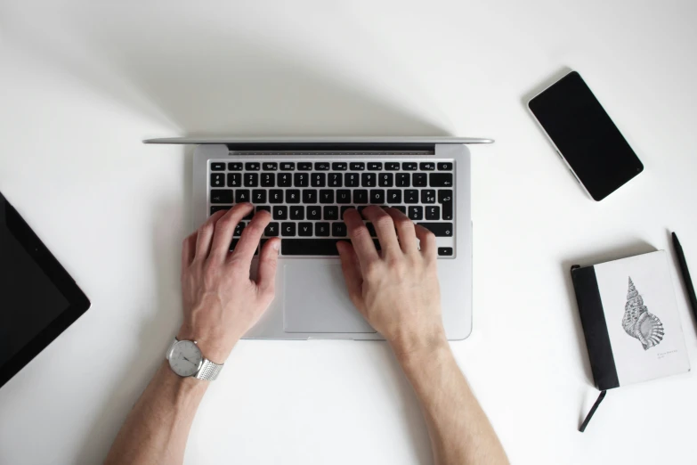 a man is typing on his laptop, surrounded by stationary objects