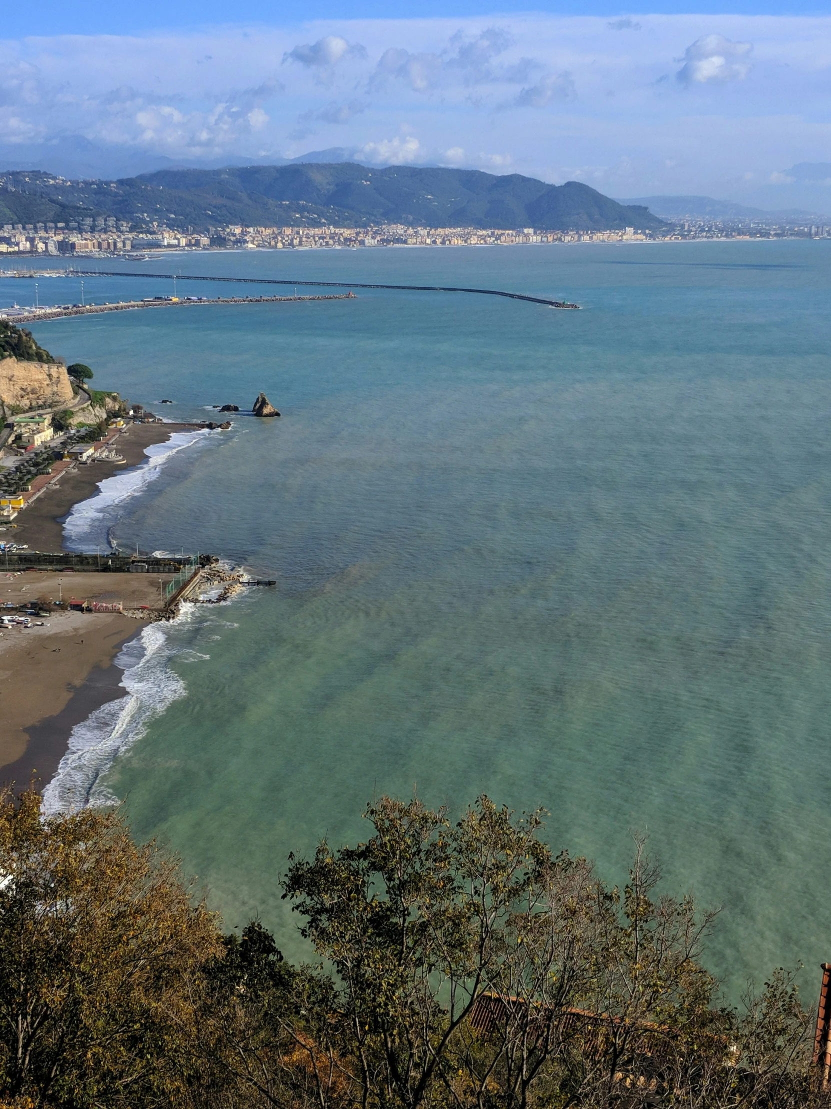 a view of an ocean shoreline, with mountains in the distance