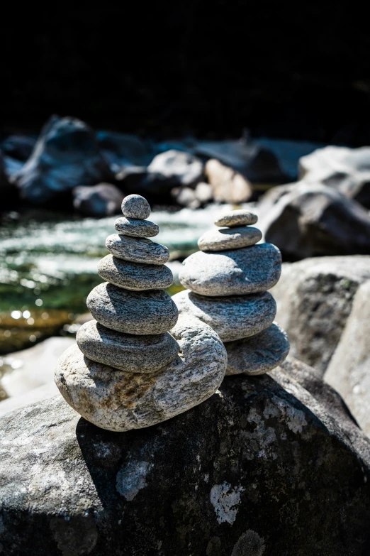 stacked rocks sitting on the edge of a stream