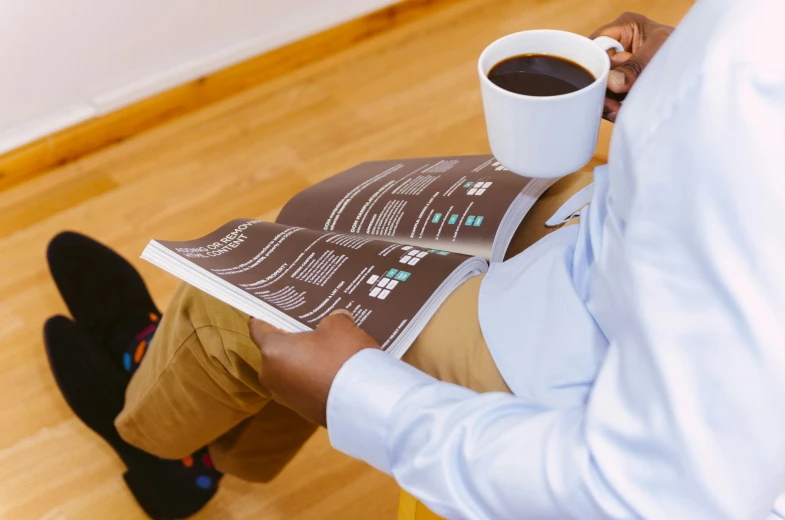 a person reading a book with coffee in front of their