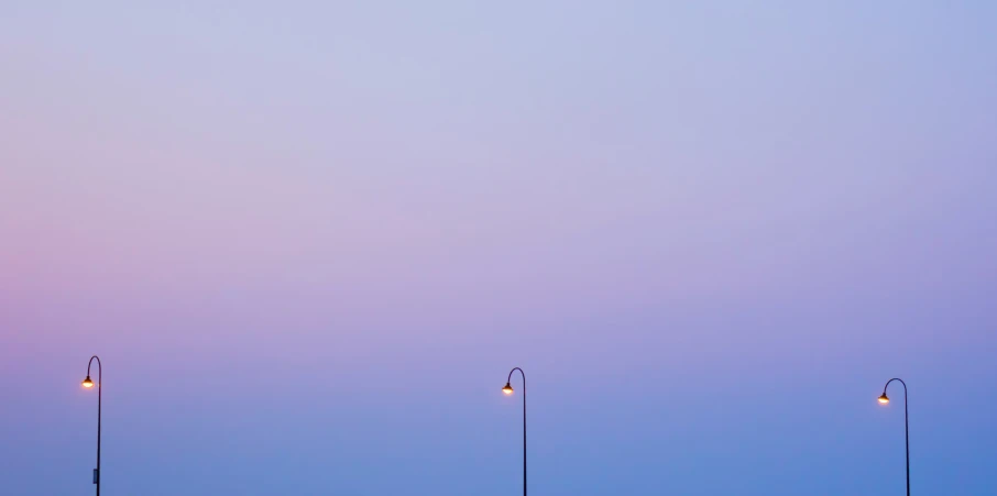 two street lights at dusk with the same bright light on