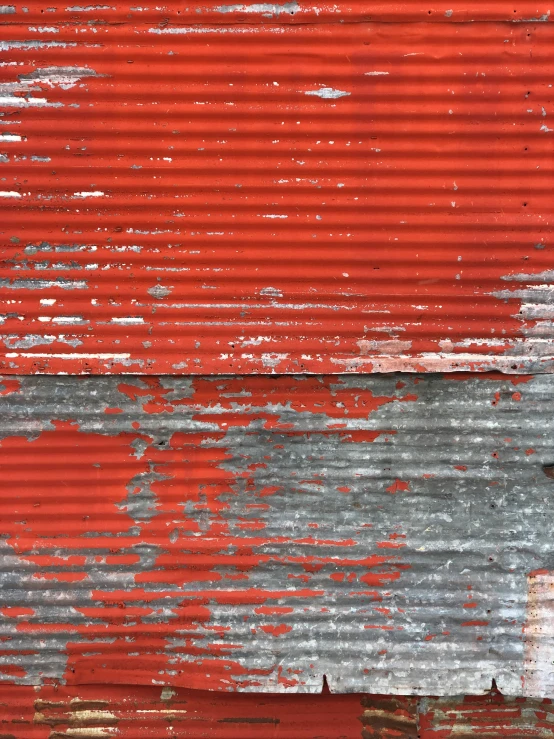 a red wall covered with old paint and rust