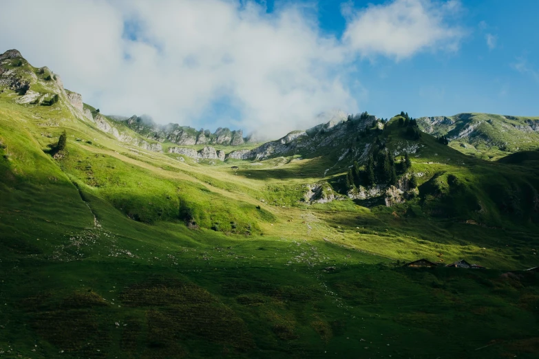 the sky is filled with clouds as it makes its way down a green hillside