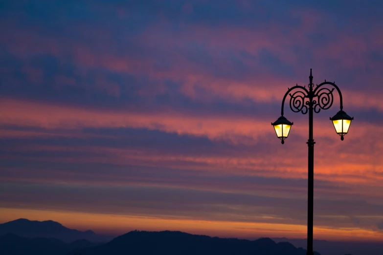 there is a street light at sunset on the mountains