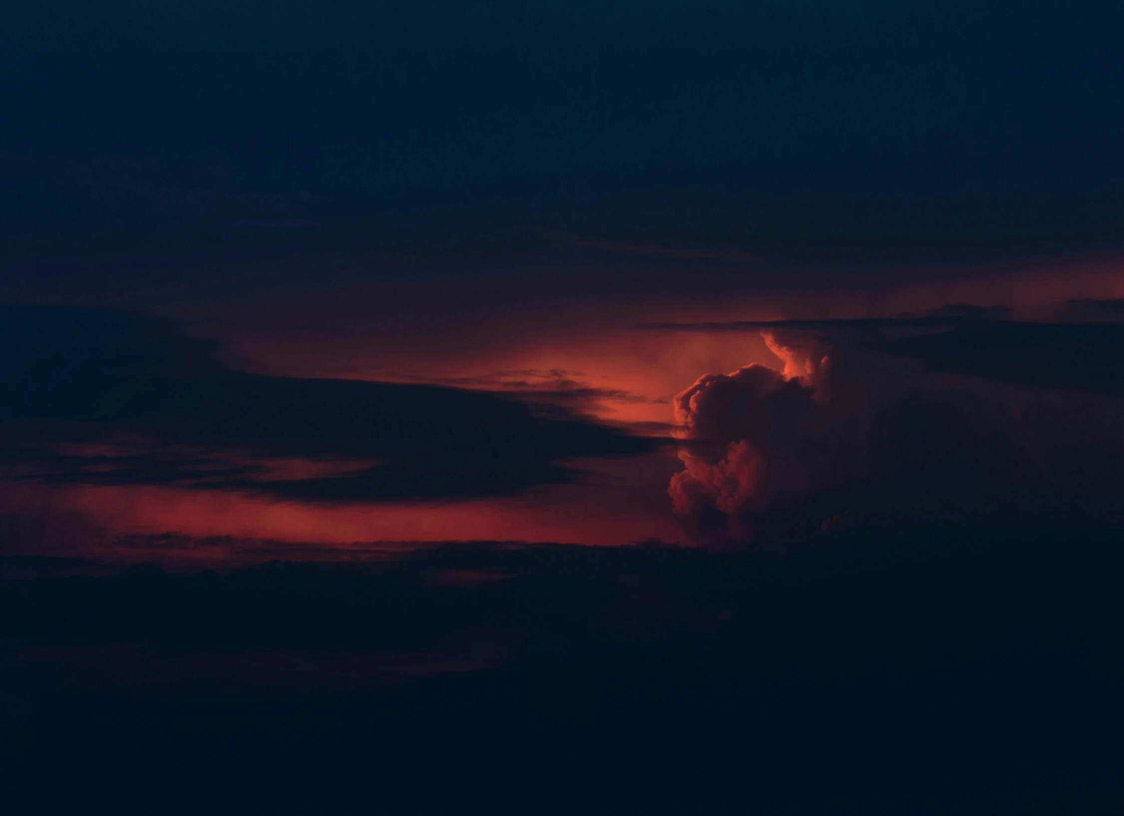 an intense red sunset behind clouds in the night sky