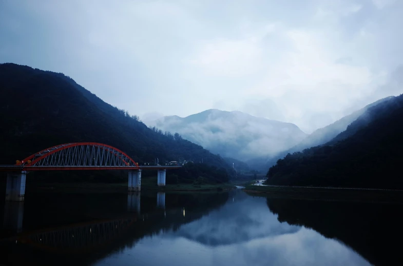 a long red bridge crosses over a wide river