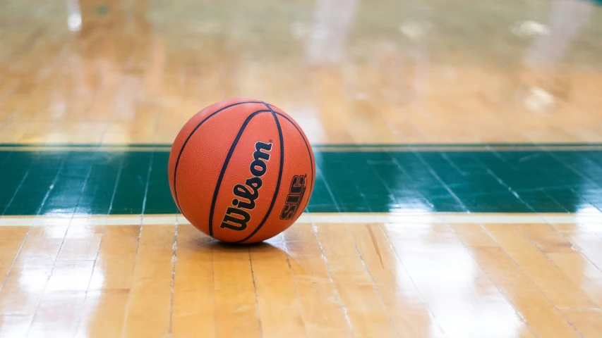 an orange basketball laying on the ground inside a gym