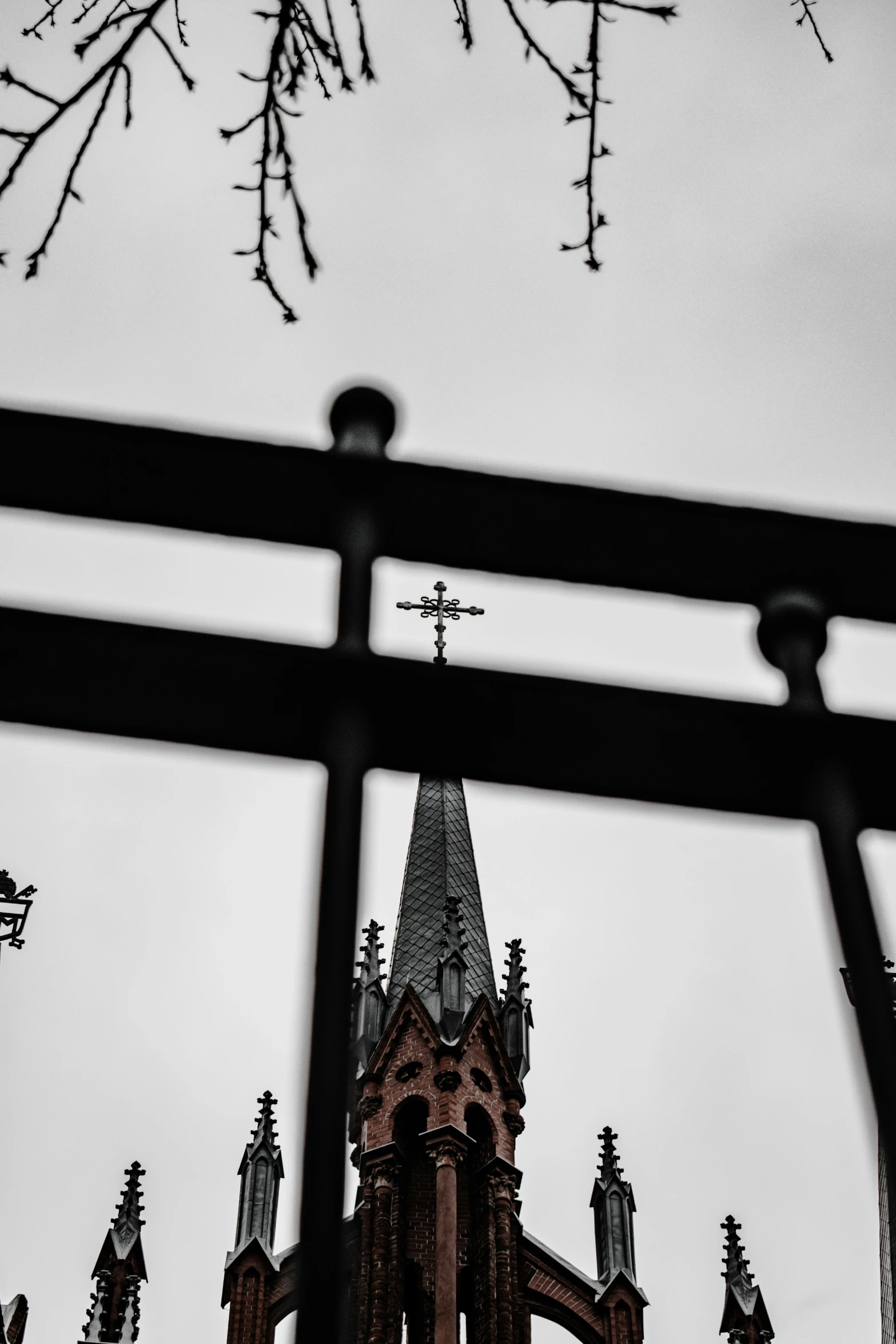 the church has steeple and weather vane as seen through an iron gate