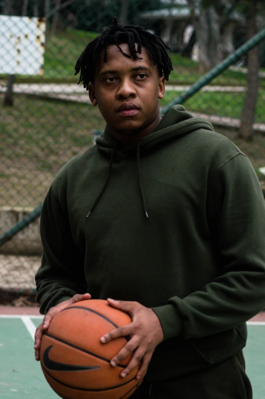 a man holding a basketball on top of a green court