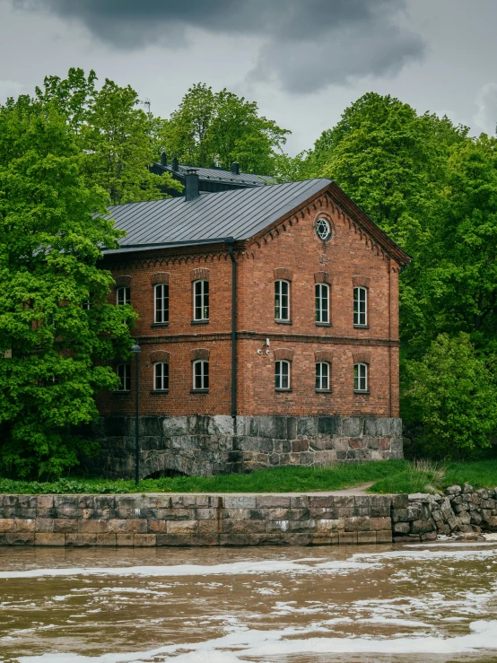 an old brick building with white windows surrounded by greenery