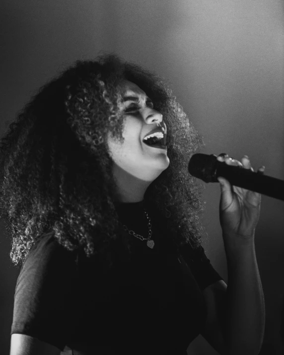 a black and white image of a female singer singing into the microphone