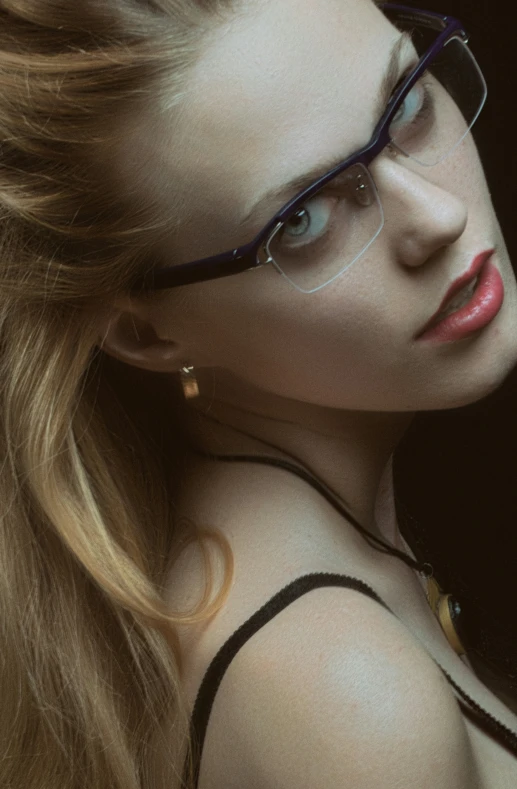 a woman with glasses and an eye ring looks into the distance