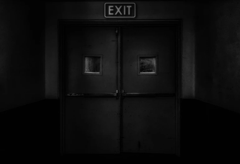 an exit sign is seen in the darkness