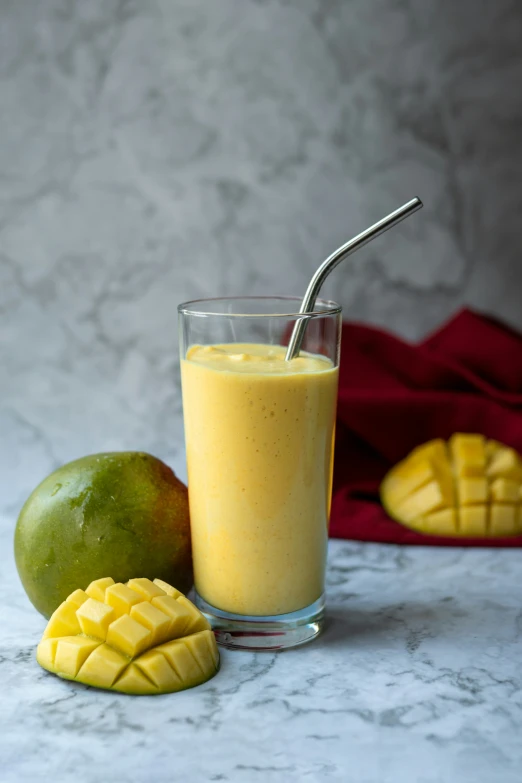 mango smoothie in a glass next to a fresh fruit