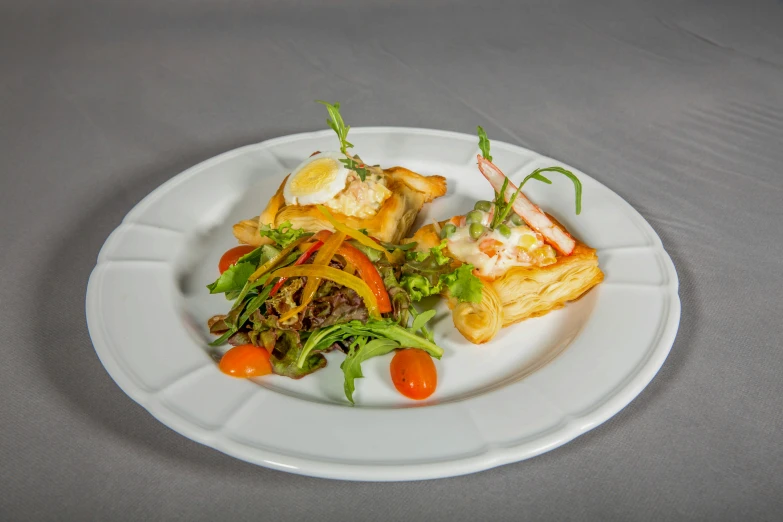a white plate topped with salad and puff pastry