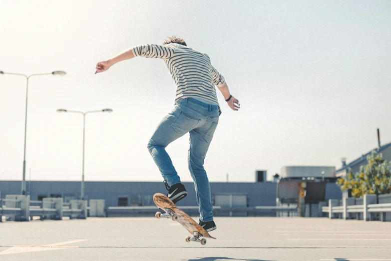 a man wearing jeans and a  shirt riding a skateboard