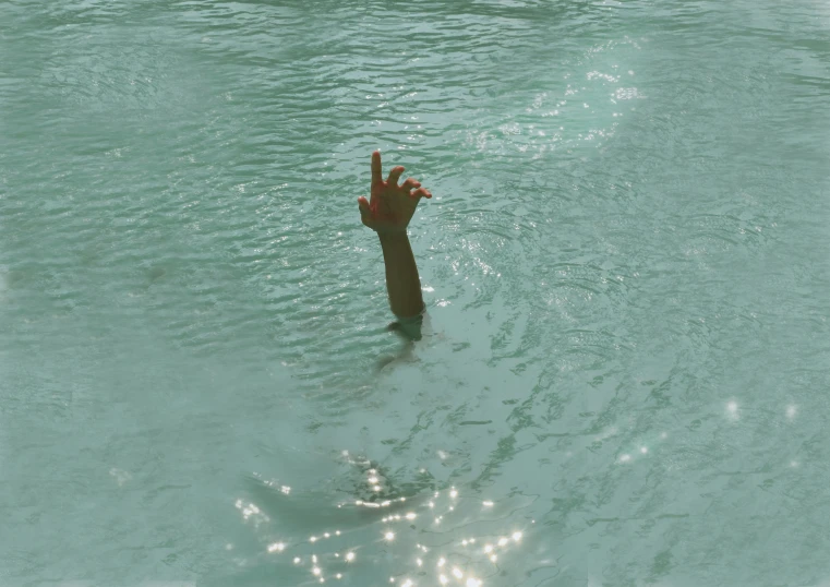 a person floating in a body of water with a hand reaching out