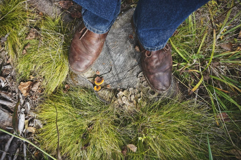 a close up po of a person with blue jeans and a brown shoe on the ground