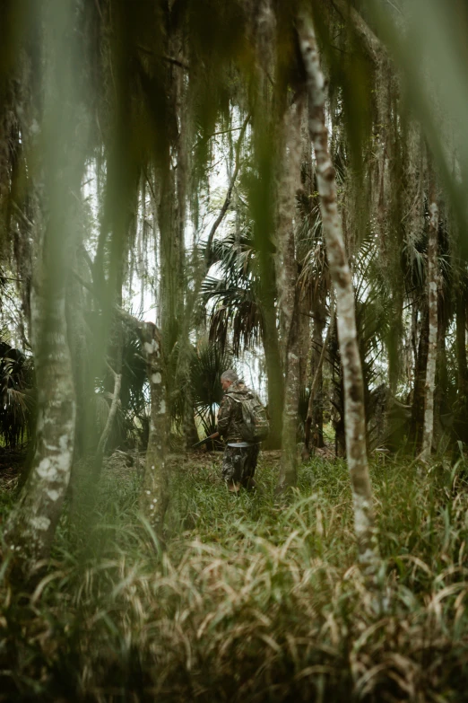 the man in camouflage is riding on his motorcycle through the woods