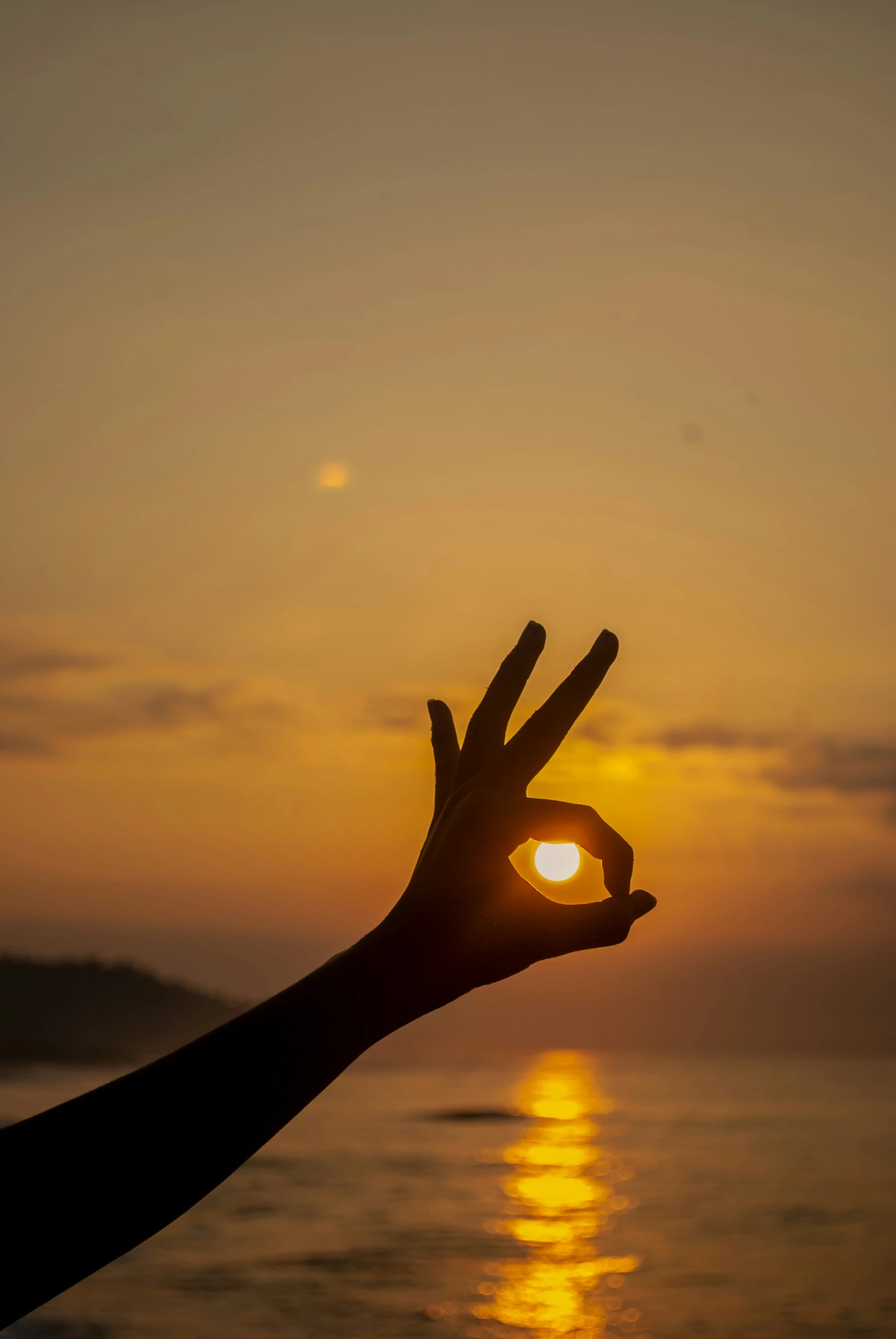 the person is holding their hand out to a sunset