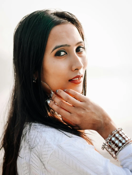 a woman with long hair holding her hand near her face