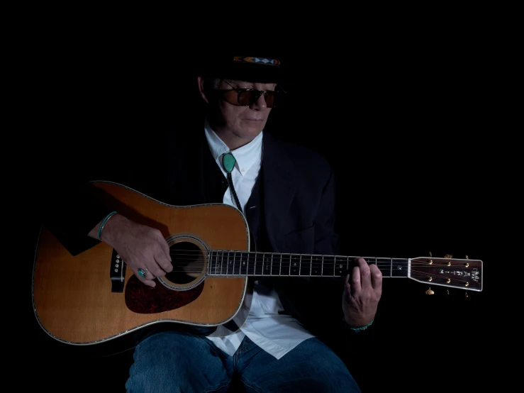 man in a suit and tie playing guitar