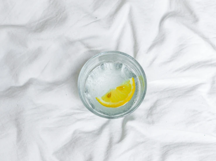 a lemon half in a clear glass on a white fabric