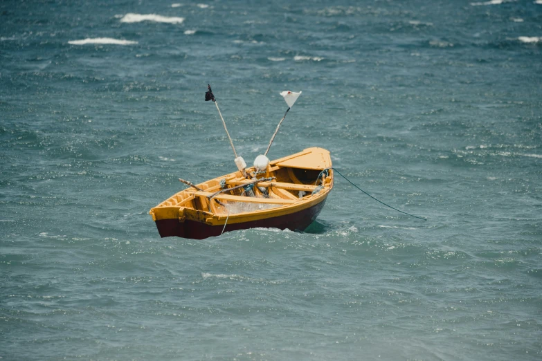 small yellow boat on open water, anchored in sea